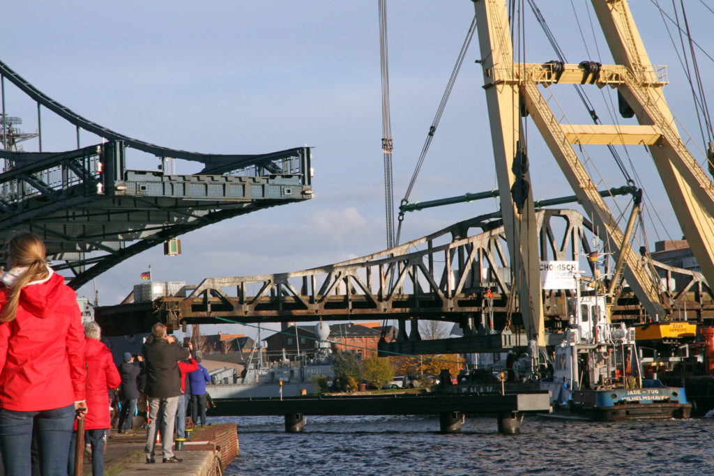 Schwimmkran "Enak" bugsiert die ausgehängte Deichbrücke durch die Kaiser-Wilhelm-Brücke. Foto: Imke Zwoch